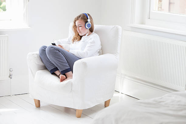 Jeune fille qui profite du chauffage dans le salon en écoutant de la musique