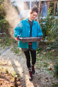 Jeune femme transportant le bac à cendres de son poêle à bois dehors