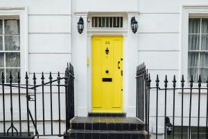 Porte d'entrée jaune vif avec escaliers et grille noirs